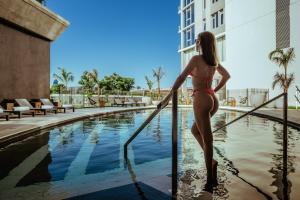 a woman in a bikini standing next to a swimming pool at SLS Buenos Aires Puerto Madero in Buenos Aires