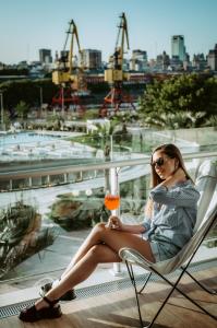 una mujer sentada en una silla con una copa de vino en SLS Buenos Aires Puerto Madero en Buenos Aires