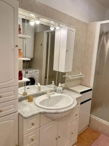 ein weißes Badezimmer mit einem Waschbecken und einem Spiegel in der Unterkunft Très bel appartement sur la plage avec grande terrace face à la mer! La Goelette in Vallauris