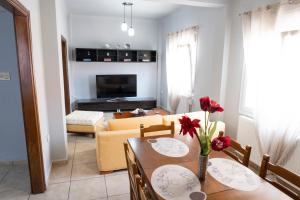 a living room with a dining room table with red flowers at House 8 in Ermoupoli
