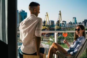 a man and a woman sitting on a balcony with a glass of wine at SLS Buenos Aires Puerto Madero in Buenos Aires