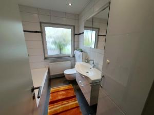a bathroom with a sink and a toilet and a window at Ferienhaus Regina im Bohnental in Lebach