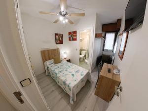 een kleine slaapkamer met een bed en een plafondventilator bij Alojamientos Pamplona in Pamplona