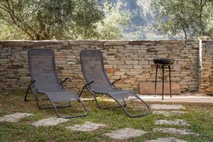 dwa krzesła siedzące obok ściany z cegły w obiekcie Casas de Xisto w mieście Raiva