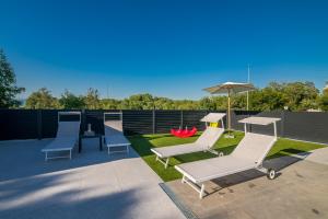 a patio with two lounge chairs and an umbrella at Apartment Aurora Island Krk Malinska in Sveti Anton