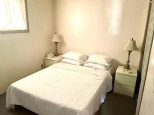 a bedroom with a white bed and two night stands at 2 BD Suite & Separate Entrance West Kelowna in West Kelowna