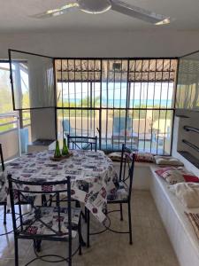 uma sala de jantar com mesa, cadeiras e janelas em Casa Ibiza Celestun em Celestún