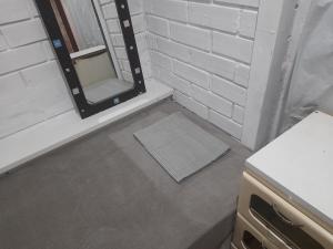 baño con espejo y pared de ladrillo blanco en Hostel Feel Home, en Blumenau