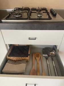 a stove top oven with utensils in a drawer at THE RANCH Apartment 2 Capalbio in Pescia Romana
