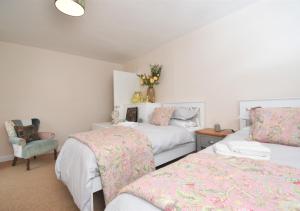 a bedroom with two beds and a chair at Sagewood Cottage in Seaton