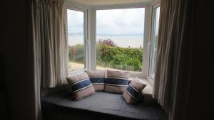 - un siège de fenêtre avec des oreillers en face d'une fenêtre dans l'établissement Cockleshell Cottage, à Mumbles