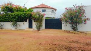 uma casa com um portão preto e dois arbustos em La case ronde avec Piscine -Ndayane em Ndéyane