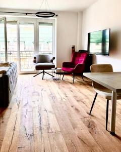 ein Wohnzimmer mit Holzböden und rosafarbenen Möbeln in der Unterkunft BaMo Studio - city living downtown in Klagenfurt am Wörthersee