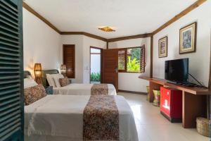a hotel room with two beds and a flat screen tv at Hotel Villa Balidendê in Barra Grande