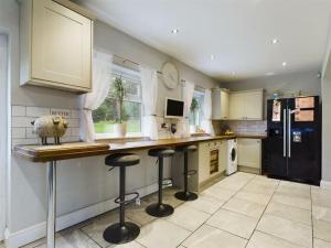a kitchen with a counter and two bar stools at -- Huge -- 5-bedroom home & Private Gym by Tailored Accommodation in Swansea