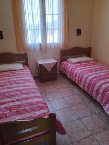 a room with two beds and a table and windows at Kali’s comfort in Karavomylos