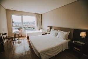 um quarto de hotel com uma cama e uma grande janela em Hotel Amantykir em Itajubá