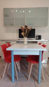 una mesa con sillas rojas y un jarrón de flores. en Casa Vacanze I Leoni Empoli, en Empoli