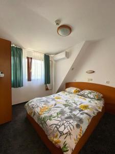 Hotel Pescarus Port Bicaz في بيكاز: غرفة نوم مع سرير مع لحاف من الزهور
