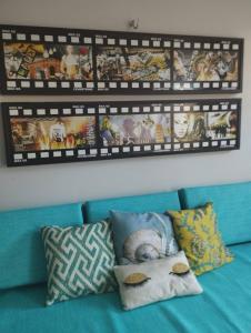 um sofá azul com almofadas e uma parede com fotografias em Flat Villagio Coqueiro em Luis Correia