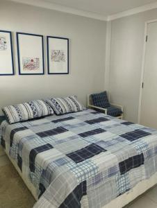 um quarto com uma cama com um cobertor azul e branco em Flat Villagio Coqueiro em Luis Correia