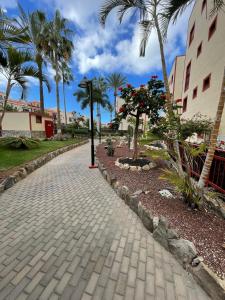 a cobblestone street with palm trees and a building at El Bohemia Tenerife zuid strand rust en 3 zwembaden in Palm-Mar