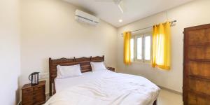 1 dormitorio con 1 cama y una ventana con cortinas amarillas en SHIKHAR BUNGLOW - A Stunning Valley View Bungalow in Mount Abu, en Mount Abu