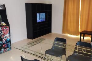 a room with a glass table and chairs and a tv at N°1 Annœullin - Appt spacieux - 2 Chambres in Annoeullin