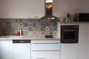 a kitchen with white cabinets and a tile wall at N°1 Annœullin - Appt spacieux - 2 Chambres in Annoeullin