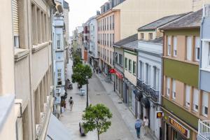 a city street with buildings and people walking down it at Apartamentos Gurugú in Ribadeo