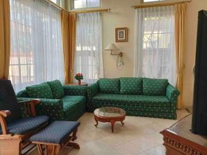 a living room with two green couches and a table at Private Villa with Swimming Pool in Babakan Madang