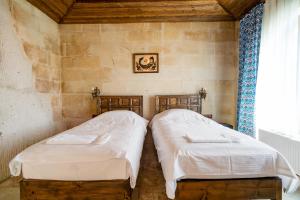 two beds sitting next to each other in a room at Cappadocia inans Cave & Swimming Pool Hot in Nevsehir