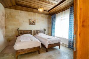 two beds in a small room with a window at Cappadocia inans Cave & Swimming Pool Hot in Nevsehir