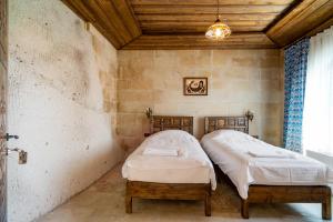 two twin beds in a room with a wooden ceiling at Cappadocia inans Cave & Swimming Pool Hot in Nevsehir