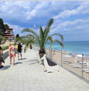 um grupo de pessoas caminhando em um passeio perto da praia em Villa Sea House 2 em Byala