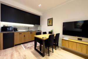 a kitchen and dining room with a table and a flat screen tv at Exquisite by Broci Apartments in Tirana