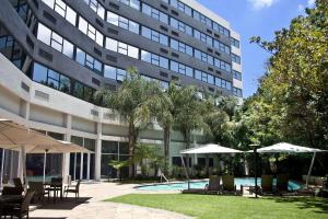 a building with a swimming pool and tables and umbrellas at Garden Court Milpark in Johannesburg