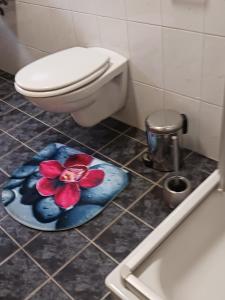 a bathroom with a toilet and a flower rug on the floor at Rustikal79 in Bleicherode