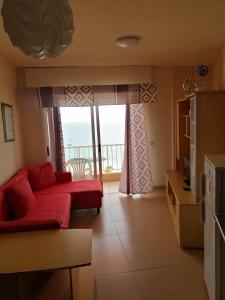 a living room with a red couch and a balcony at Apartamentos Vista Bahia in Los Cristianos