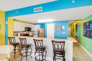 a room with chairs and a kitchen with blue walls at Majestic Beach Towers 2013 in Panama City Beach