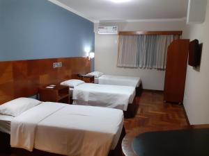 a hotel room with two beds and a television at Hotel Amantykir in Itajubá