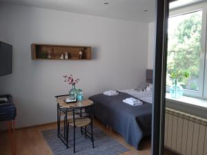 a bedroom with a bed and a table and a window at Apartamenty Wiejska 126 in Sosnowiec