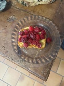 a cake with raspberries on a glass plate on a table at Oh ! Fleurs des champs in Chaumont-sur-Tharonne