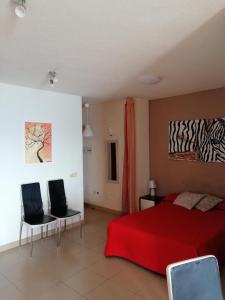 ロス・クリスティアーノスにあるApartamentos Vista Bahiaのベッドルーム1室(赤いベッド1台、椅子2脚付)