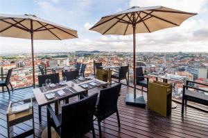ein Restaurant mit Tischen und Sonnenschirmen auf einem Balkon in der Unterkunft Hotel Dom Henrique - Downtown in Porto