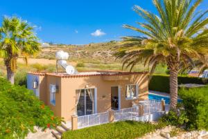 una pequeña casa con palmeras delante en Villa Athina, en Peyia