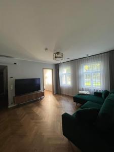 een woonkamer met een groene bank en een flatscreen-tv bij Mere in Pärnu