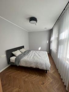 een witte slaapkamer met een bed en een houten vloer bij Mere in Pärnu