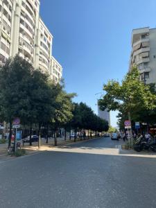 una strada vuota in una città con alberi ed edifici di Exquisite by Broci Apartments a Tirana