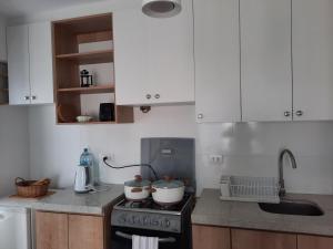 uma cozinha com armários brancos e um forno com placa de fogão em Loft acogedor con área de parrilla y piscina em Punta Hermosa
